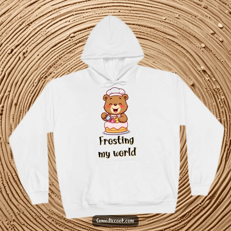Funny happy bear chef decorating a cake with colorful frosting swirls, depicted on a soft and warm hoodie, perfect for sweet moments.