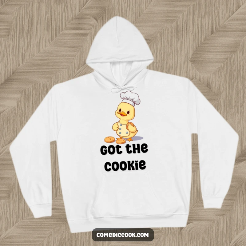 Funny smiling duckling chef carefully gathering a tiny cookie, depicted on a warm and humorous hoodie.
